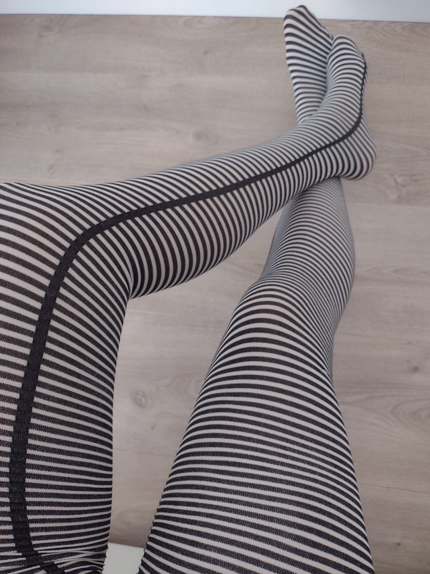 Close-up of black and cream fine horizontal stripe tights worn on legs