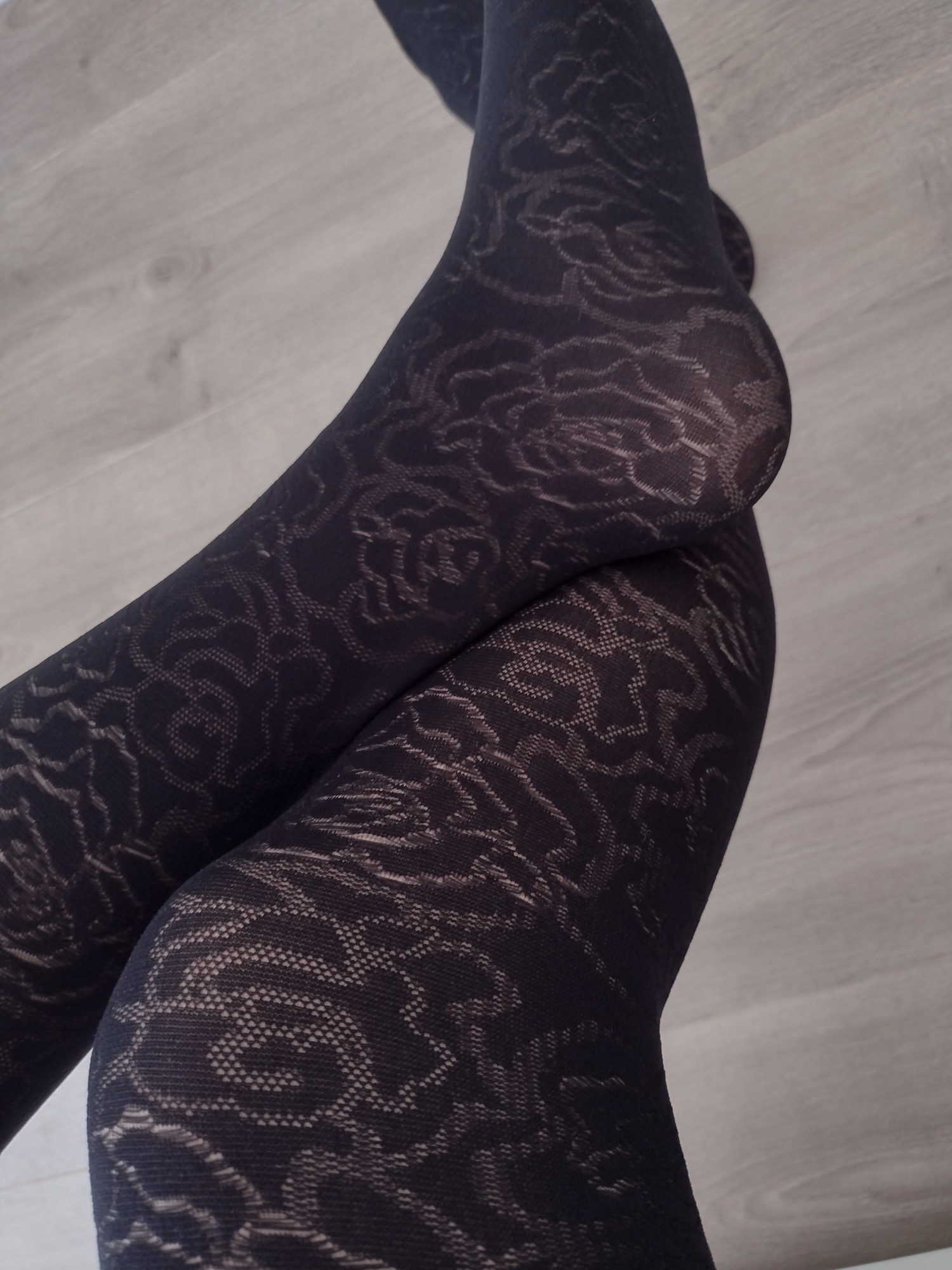 Close-up detail of the rose floral jacquard knit pattern on black tights