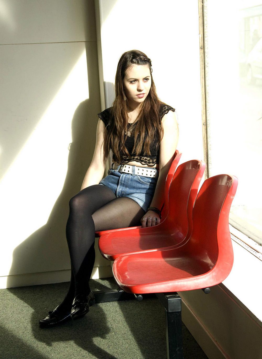 Black sheer tights with a black lace crop top, denim shorts, and patent loafers