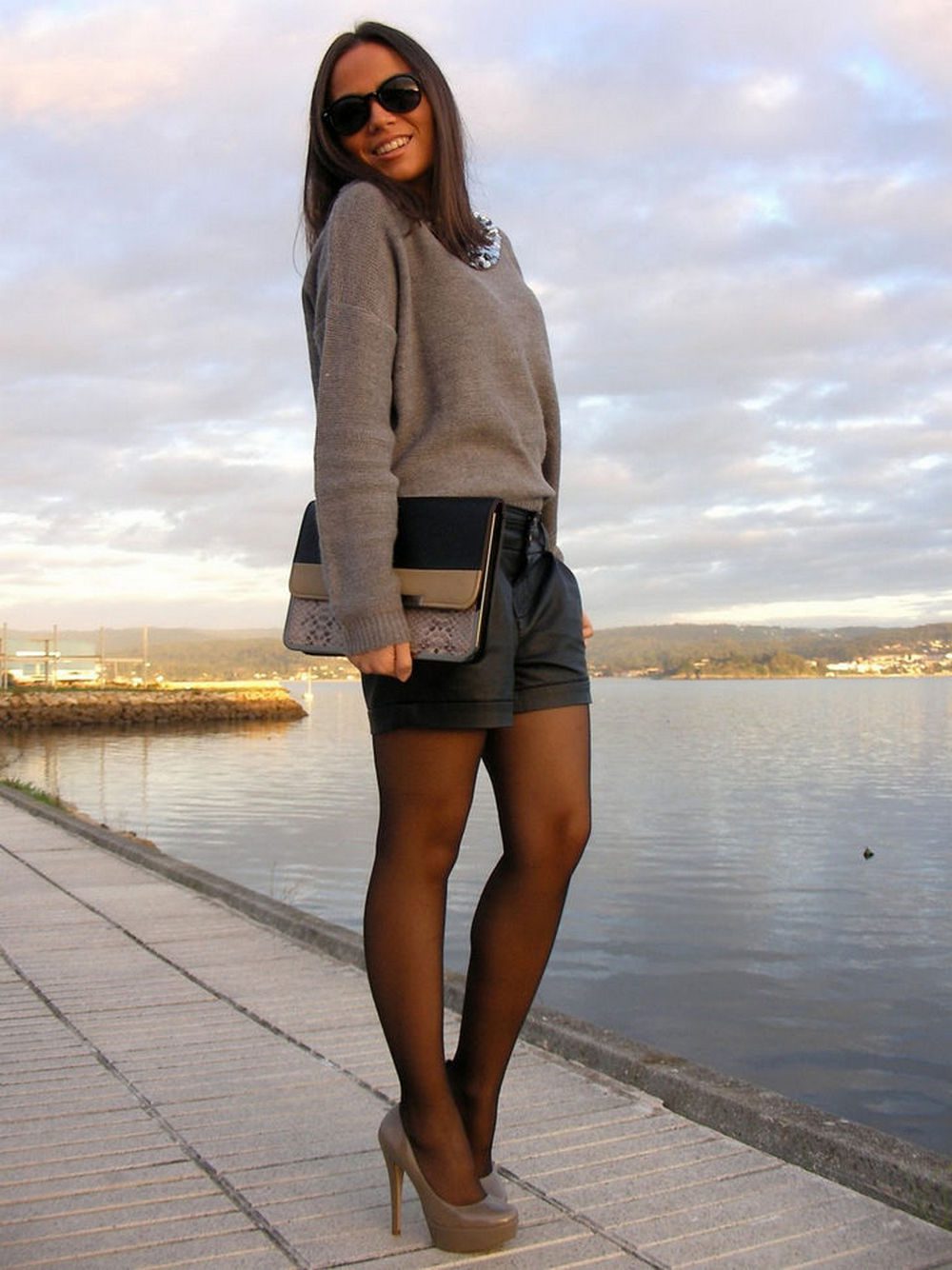 Black sheer tights with black leather-look shorts, a grey knit sweater, and platform pumps