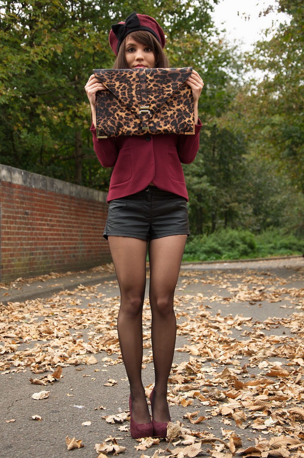 Black sheer tights with black vinyl shorts, a burgundy blazer, a matching beret, and suede pumps