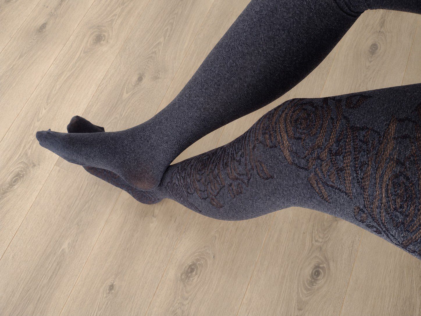 Full leg view of charcoal grey tights with a rose floral jacquard pattern, retouched background