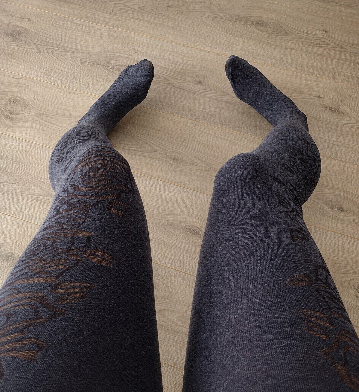 Full leg view of charcoal grey floral rose tights worn, retouched background