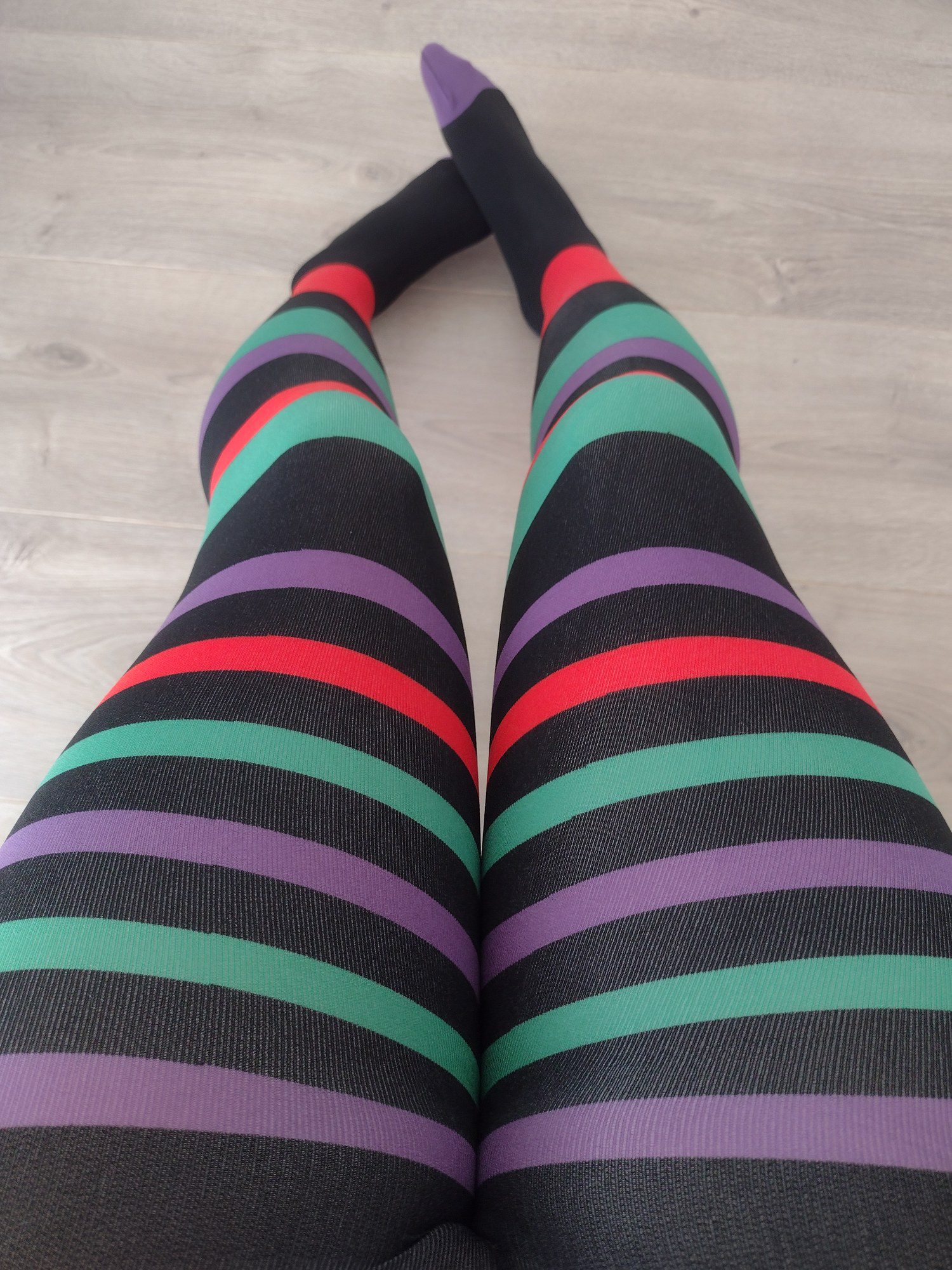 Black, purple, red and teal horizontal stripe tights, worn on legs