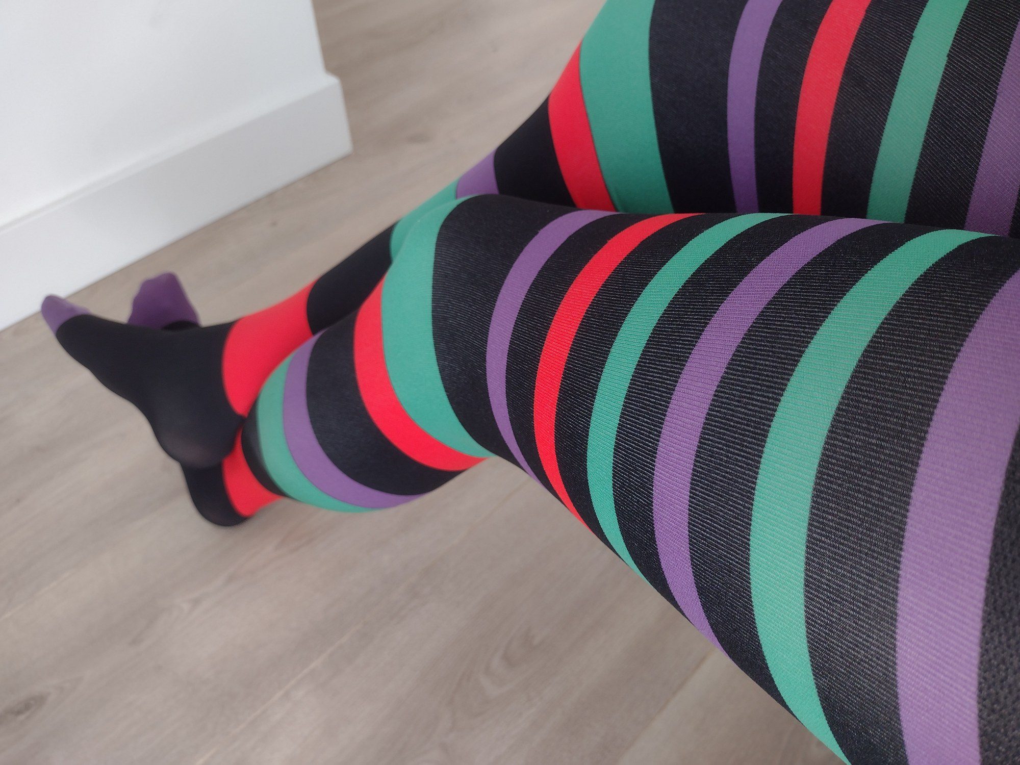 Close-up of jewel-tone horizontal stripe tights worn on legs