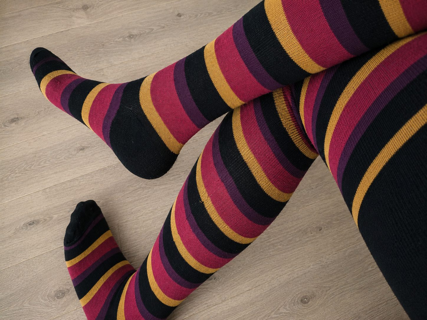 Black, gold, pink and purple horizontal stripe tights, worn on legs, retouched background