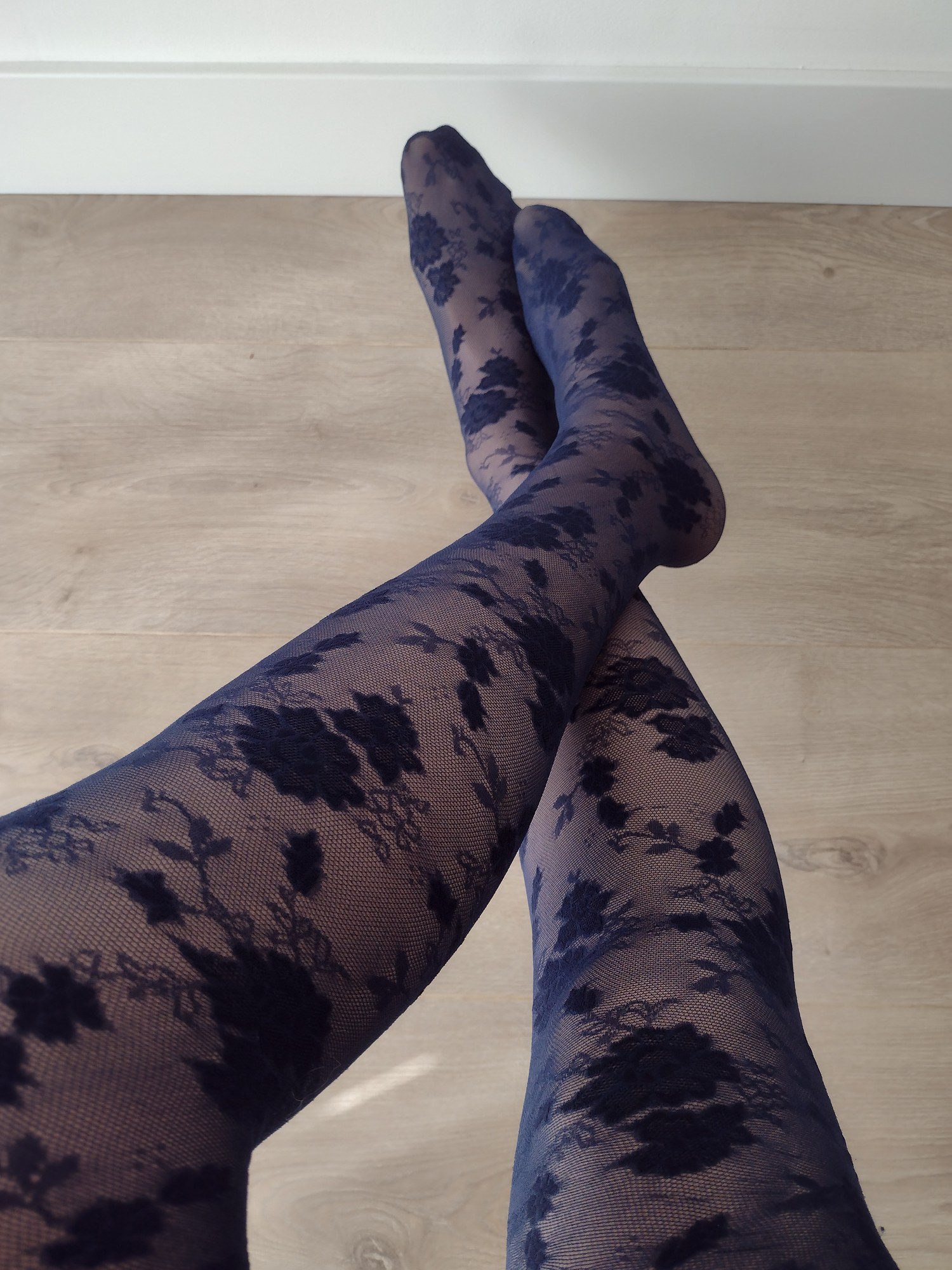 Navy sheer mesh tights with a bold black floral lace print, worn on legs