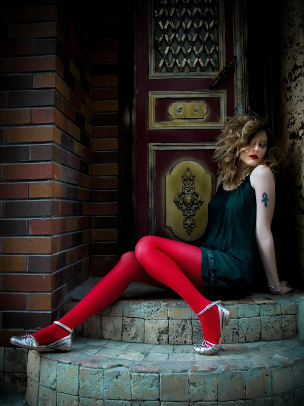 Bright red tights with a dark green slip dress and metallic silver flats, sitting on stone steps