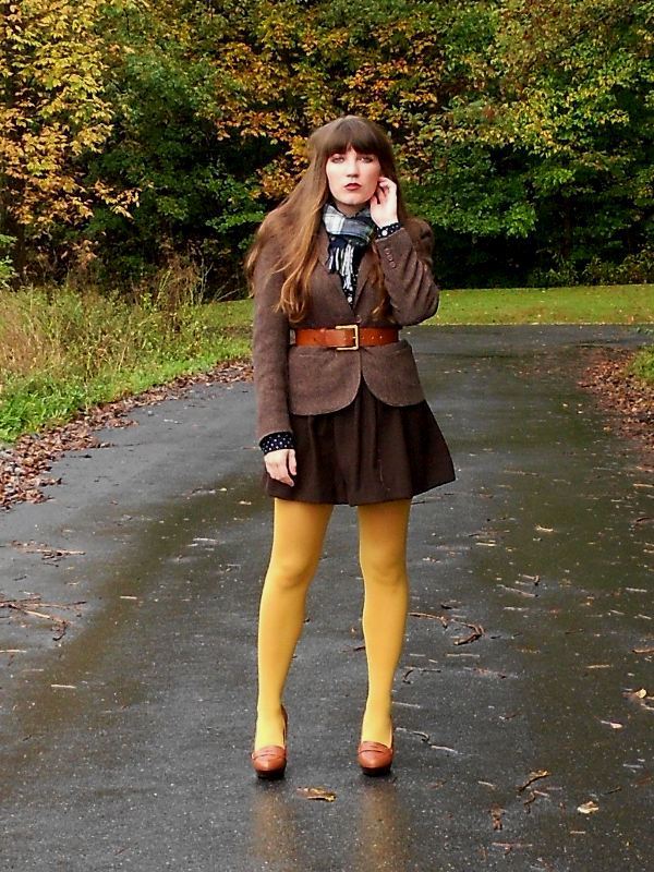 Mustard yellow tights with a brown tweed blazer, brown skirt, plaid scarf, and brown loafer heels, outdoors in autumn