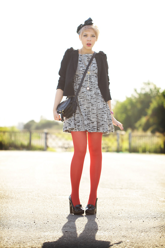 Bright red tights with a grey tweed-print dress, black cropped jacket and black bow platform heels