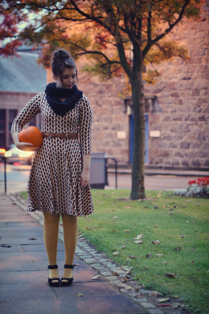 Mustard yellow tights with a black, white, and red printed dress, navy infinity scarf, and black platform heels