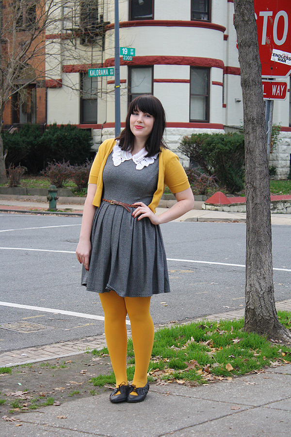 Mustard yellow tights with a matching mustard cardigan, grey dress with a white collar, and black and yellow oxford flats
