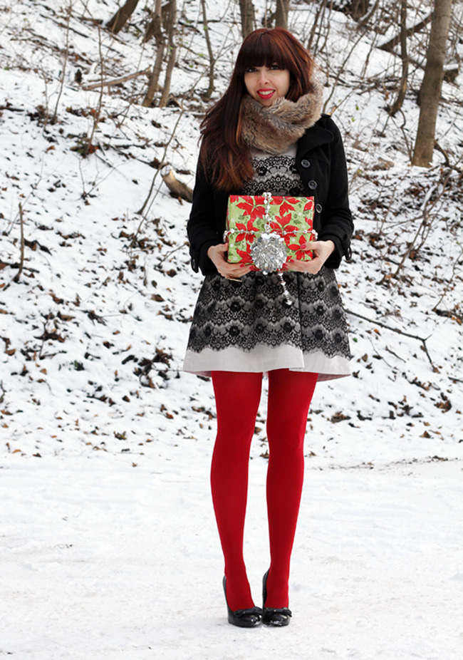 Bright red tights with a black lace-overlay dress, faux-fur collared coat, and black ballet flats, standing in snow