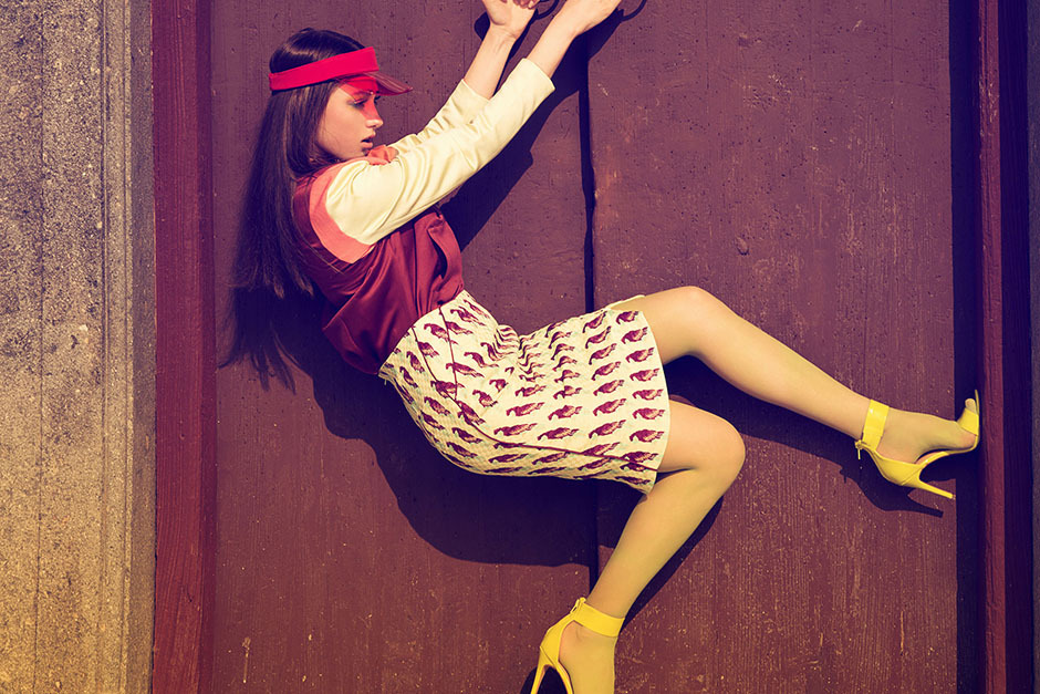 Pale yellow tights with a burgundy satin top, cream sleeves, a bird-print skirt, a pink visor, and yellow strappy heels