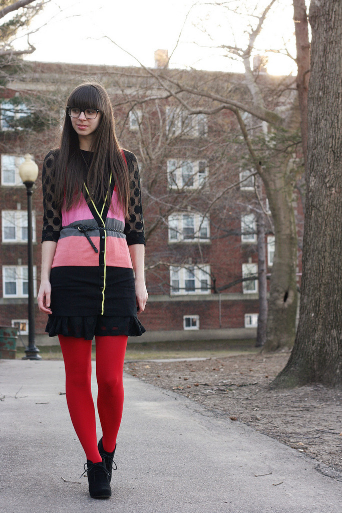 Opaque red tights with a pink, coral and black polka-dot color-blocked top, black skirt, and black lace-up booties