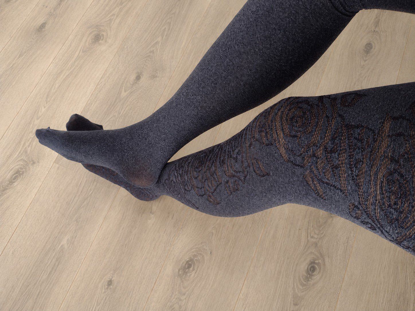 Full leg view of charcoal grey tights with a rose floral jacquard pattern, retouched background
