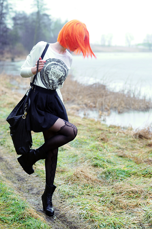 Black faux thigh-high tights with a lace scallop-print top, worn with a white graphic sweatshirt, a black pleated skirt and black platform ankle boots by a misty lake
