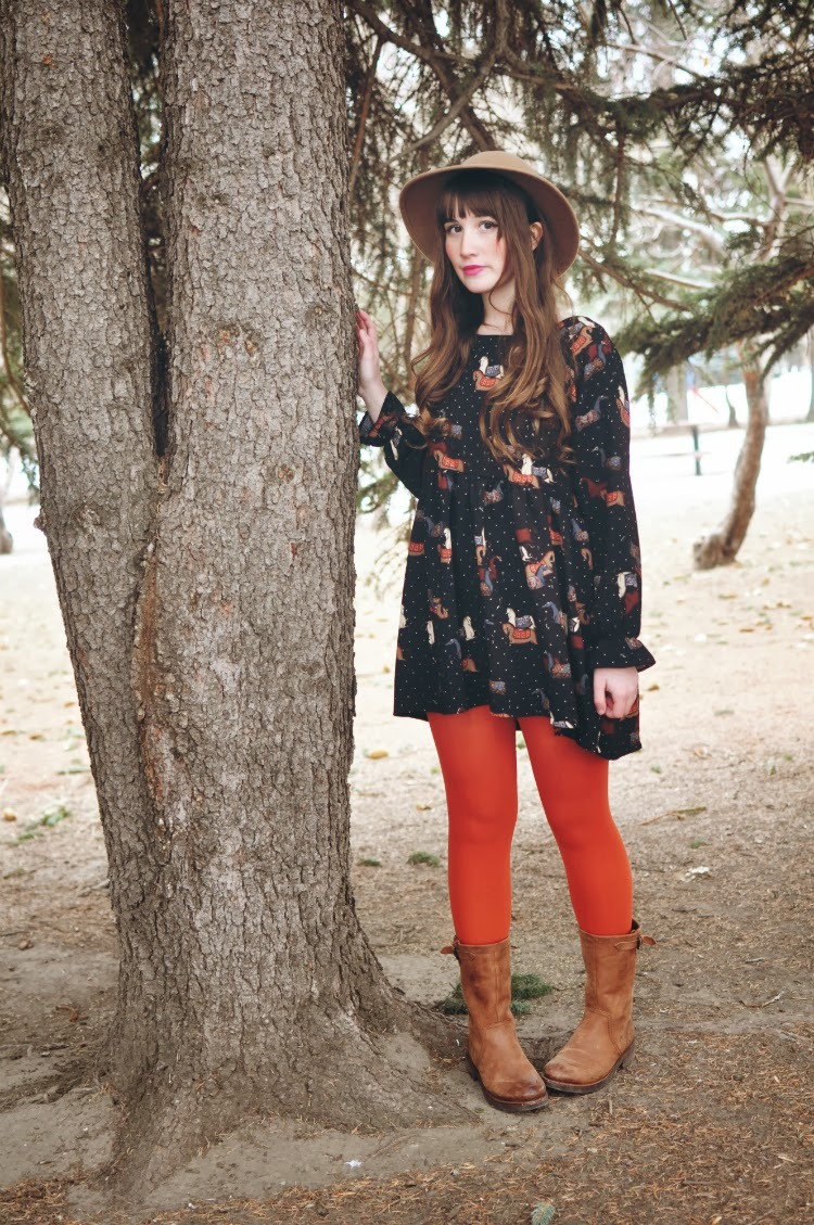 Orange tights with tan leather western-style boots, a black printed dress and a felt hat