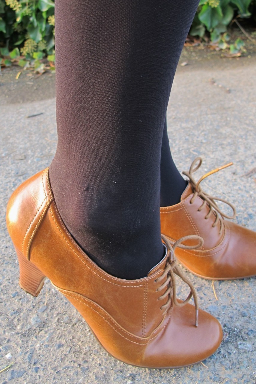 Close-up of opaque black tights with cognac leather heeled lace-up booties