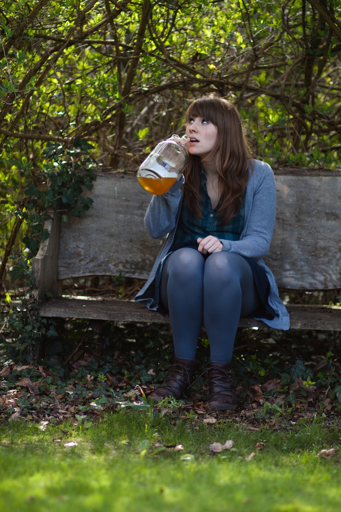 Muted blue tights with dark brown leather lace-up boots and a grey knit cardigan, sitting on a bench