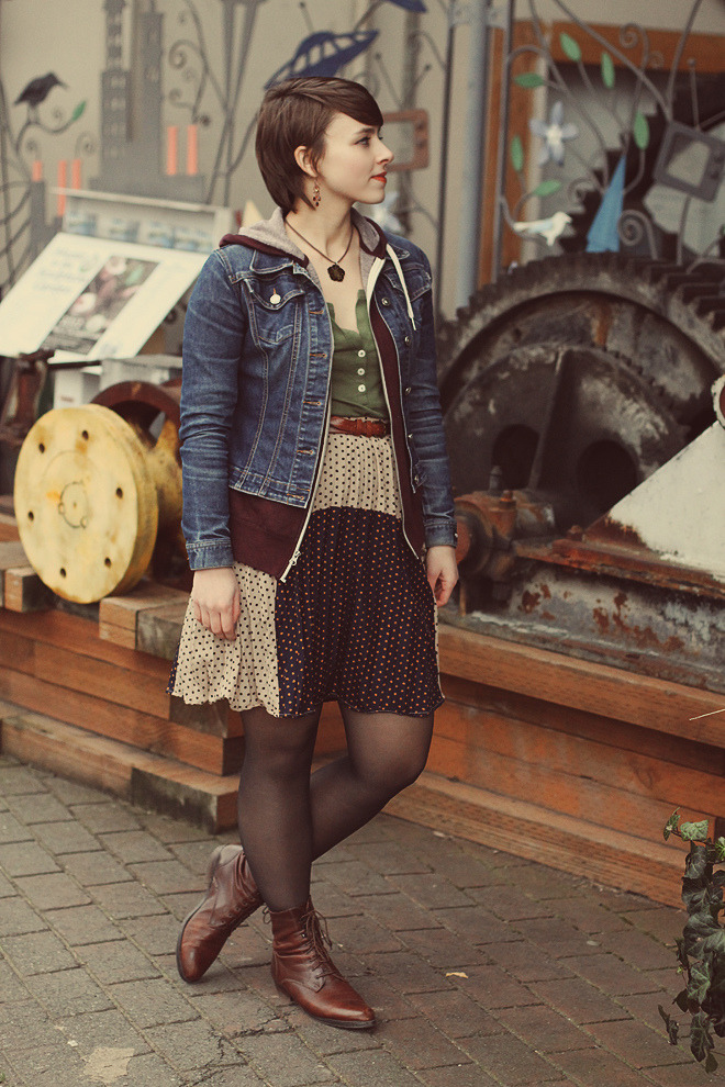 Black sheer tights with dark brown leather lace-up boots, a dotted skirt, a green top and a denim jacket