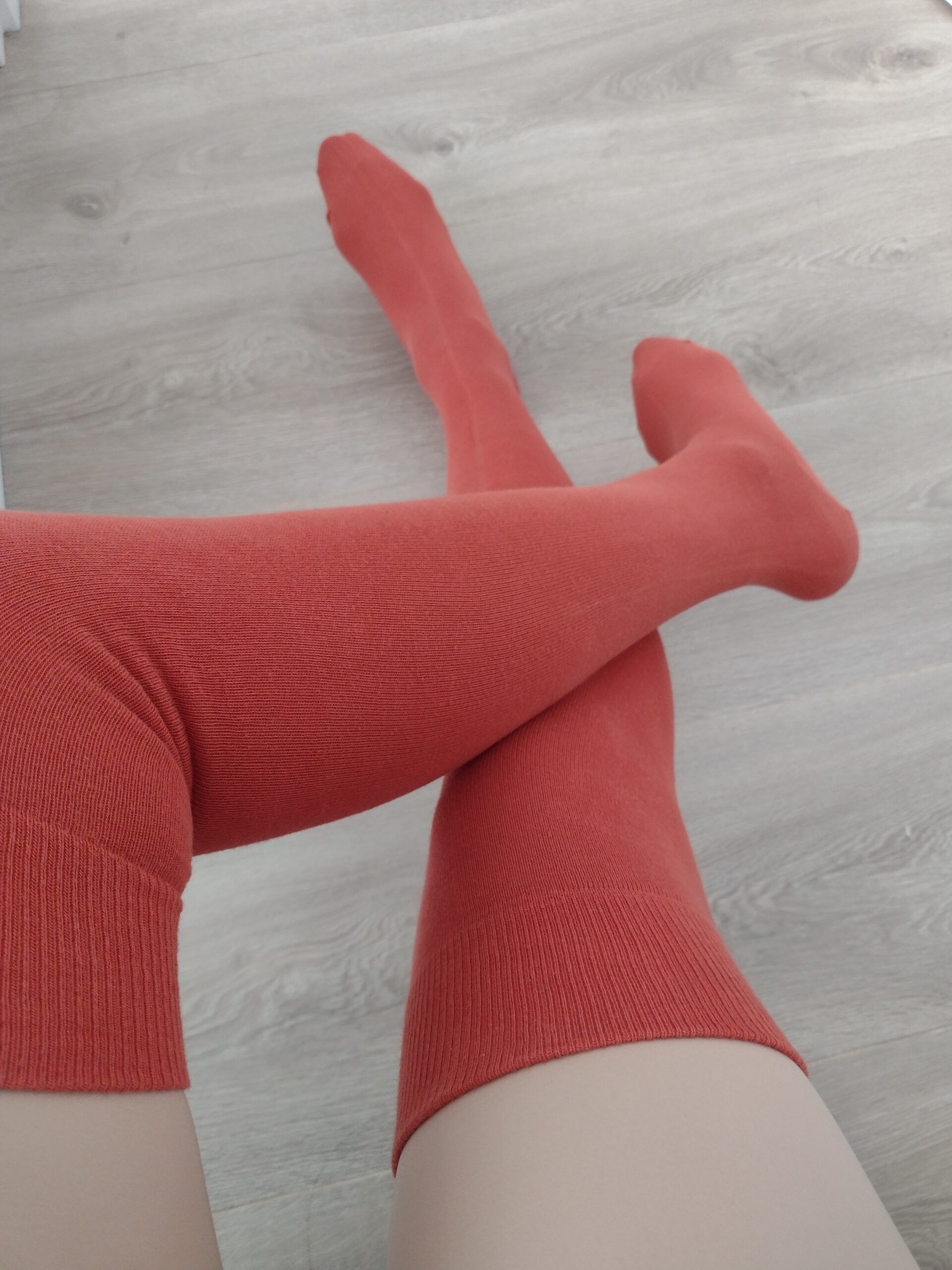 Terracotta ribbed over-the-knee socks on wood floor