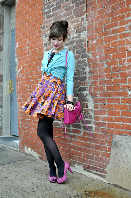 Woman in black tights with magenta peep toe pumps and a floral skirt, with a mint cardigan and pink bag