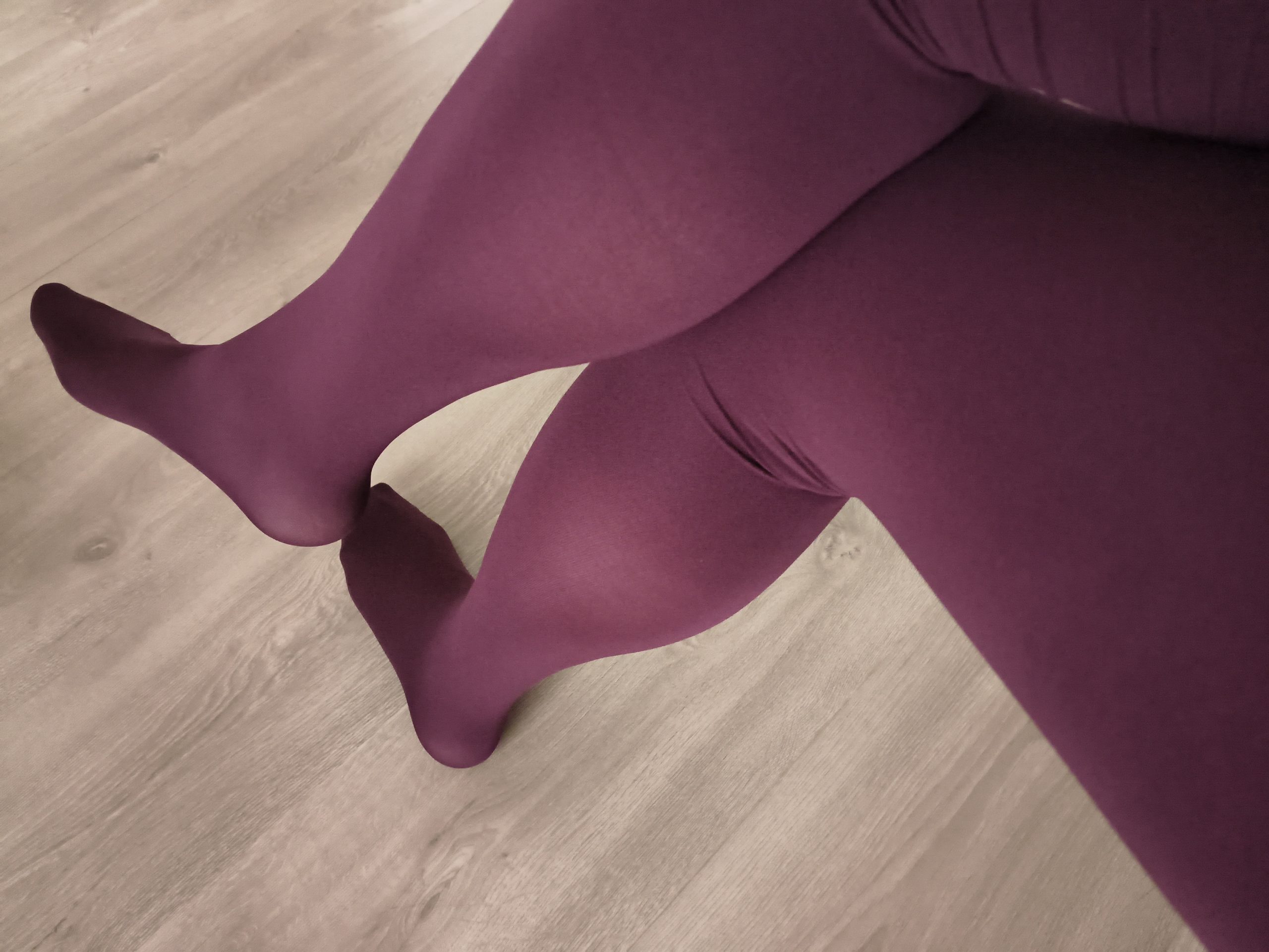 Woman in Yirane burgundy 80D opaque tights, feet crossed, close-up on a wooden floor