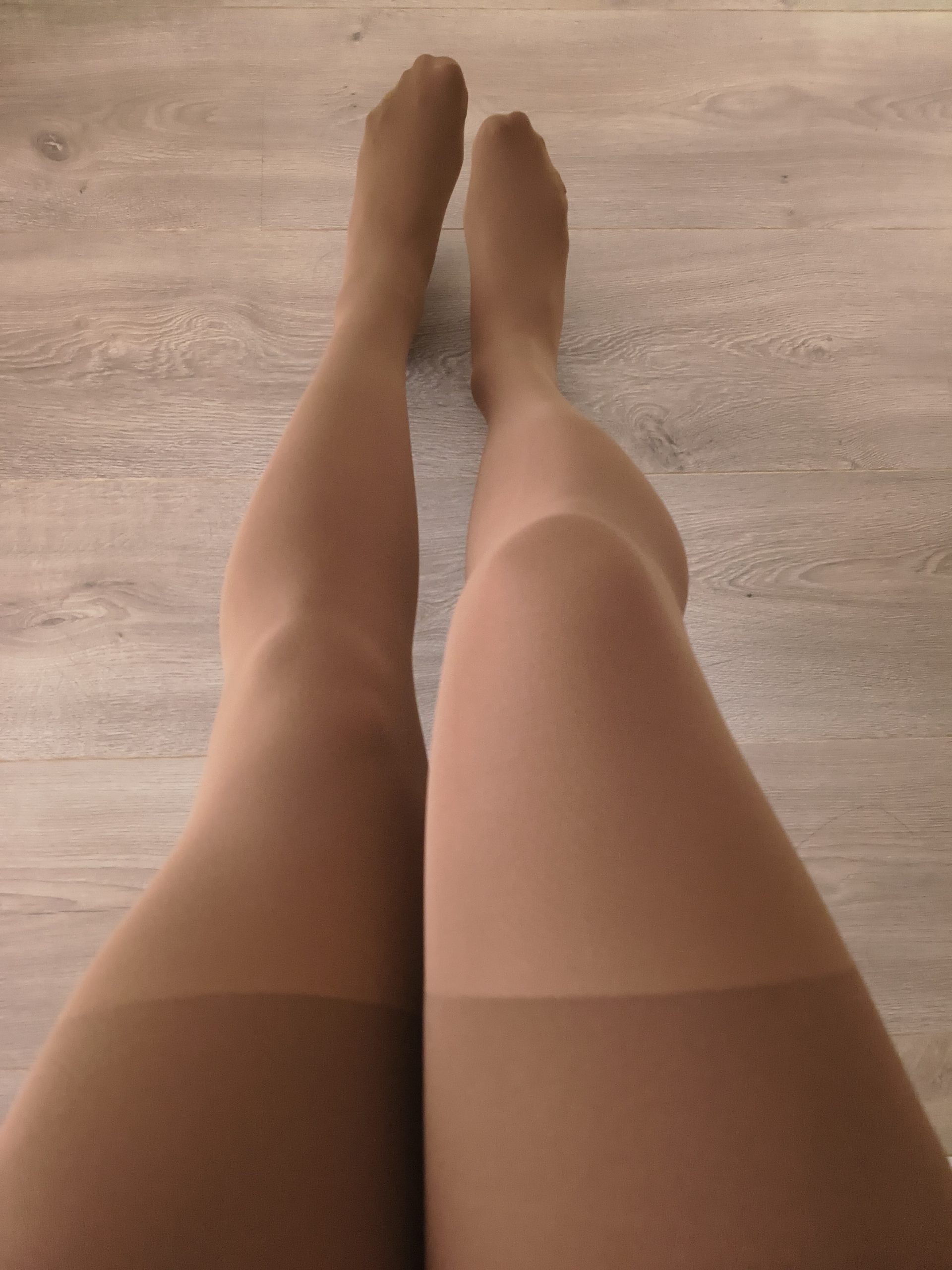 Woman in Yirane cocoa brown 80D opaque tights, legs crossed, sitting on a wooden floor