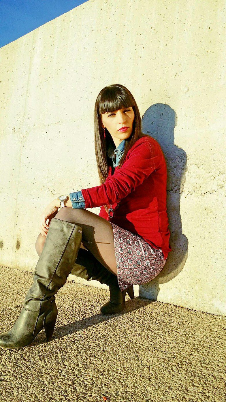 Sheer black pantyhose, long high heel boots, patterned skirt and red cardigan worn by Veronica